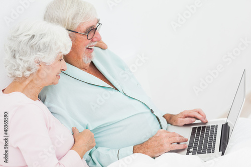 Couple with laptop in bed