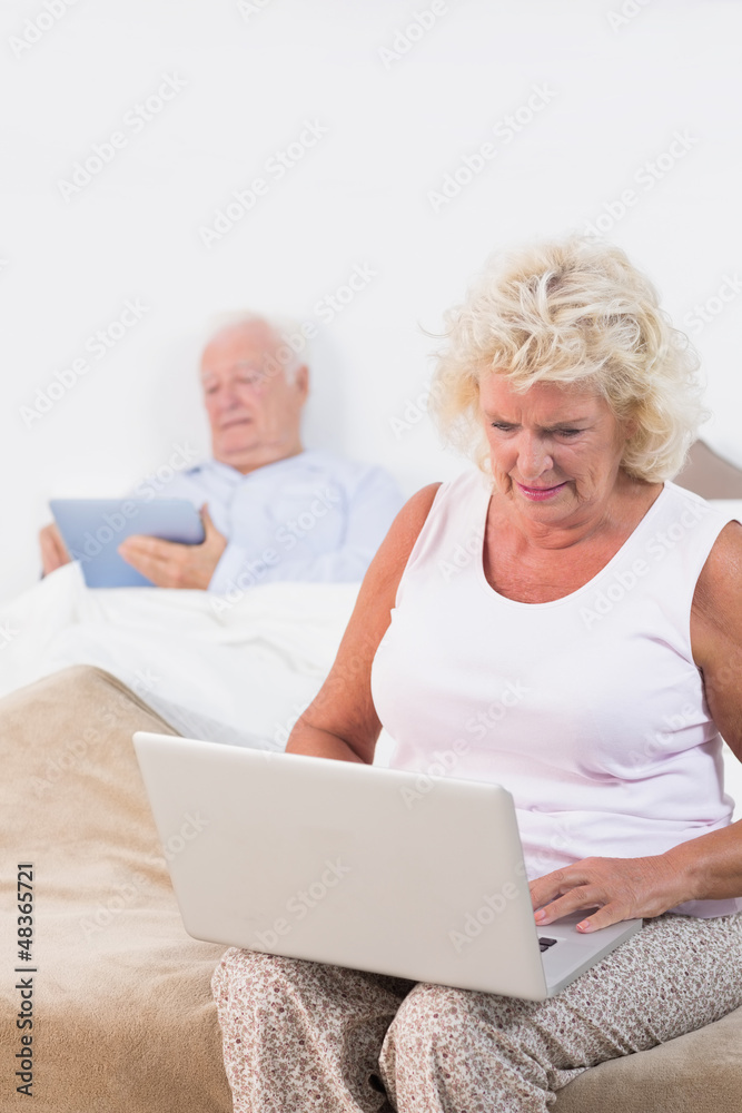 Old couple using a tablet and the laptop