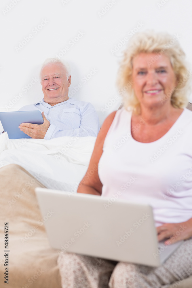 Happy old couple using a tablet and the laptop Happy old couple using a tablet and the laptop