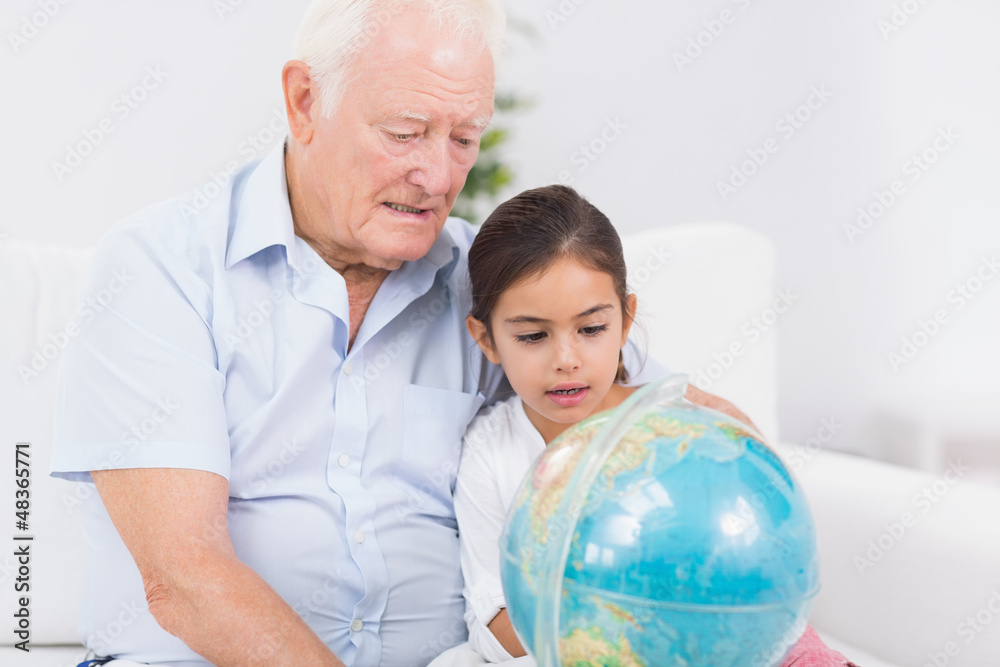 Obraz premium Granddaughter and grandfather with globe