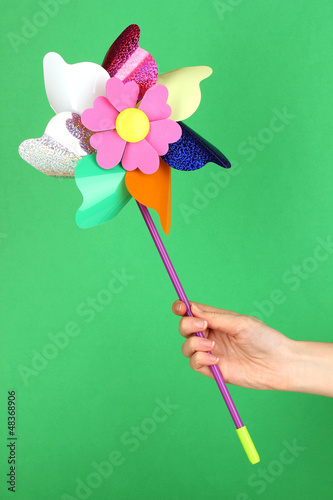 Colored pinwheel in hand on green background © Africa Studio