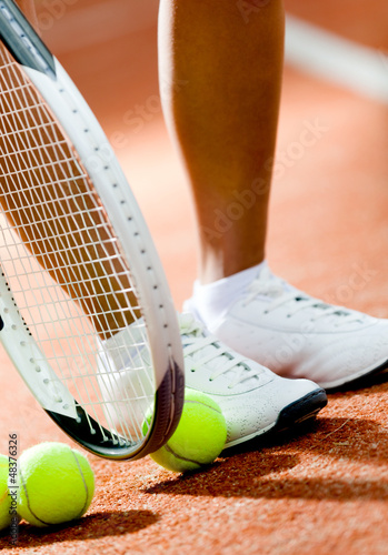 Legs of sportive girl near the tennis racket and balls © Karramba Production