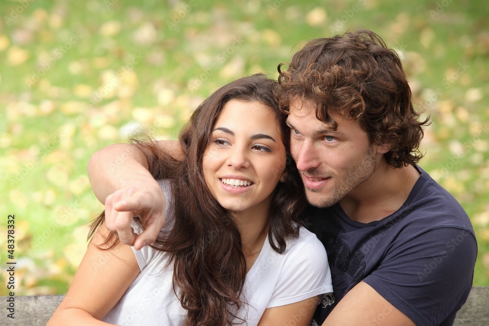 Couple in a park watching where the man points Couple in a park watching where the man points