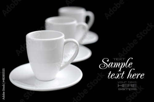 Empty white coffee cups and saucers on black background