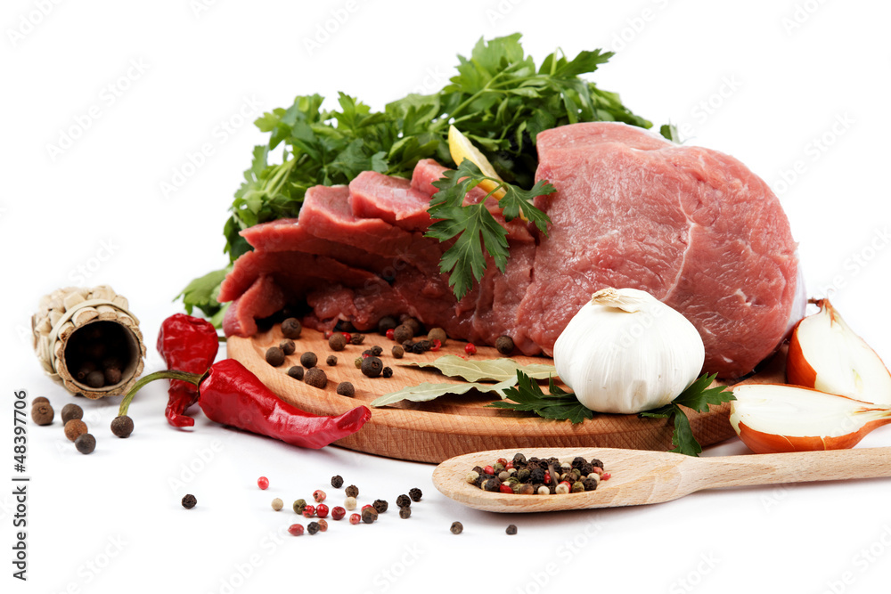 Raw meat, vegetables and spices on a wooden cutting board isolat