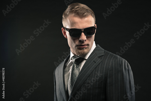 Fashion man in suit wearing sunglasses. Studio shot.