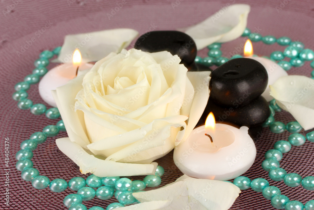spa stones with flower and candles in water on plate spa stones with flower and candles in water on plate