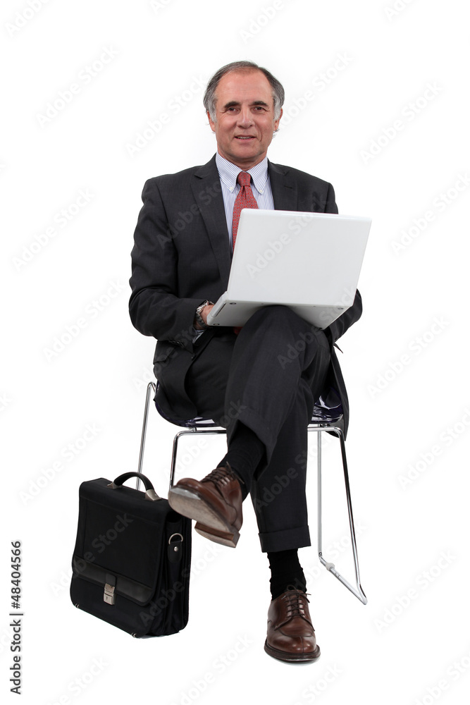 Middle-aged businessman sat in chair using laptop Middle-aged businessman sat in chair using laptop