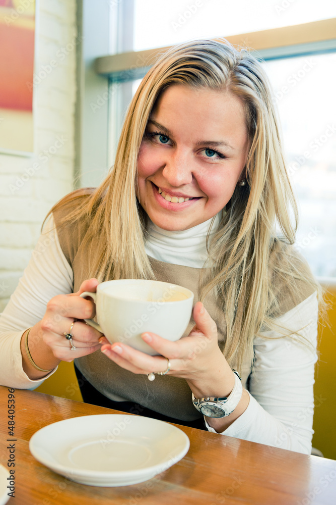 smiling young woman drinking coffee from a white cup smiling young woman drinking coffee from a white cup