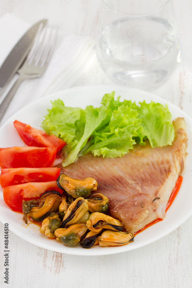 fish with seafood and salad on the white plate