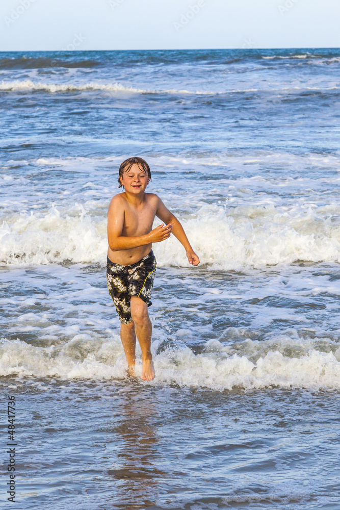 young boy running through the water at the beach