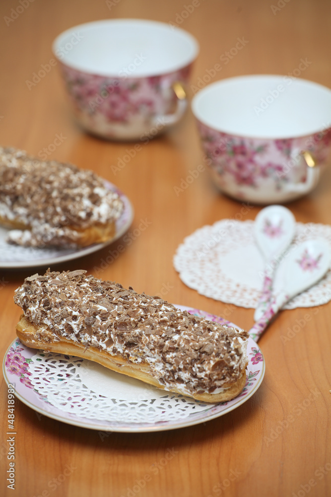 Eclairs for a couple on a wooden table with pink cups Eclairs for a couple on a wooden table with pink cups