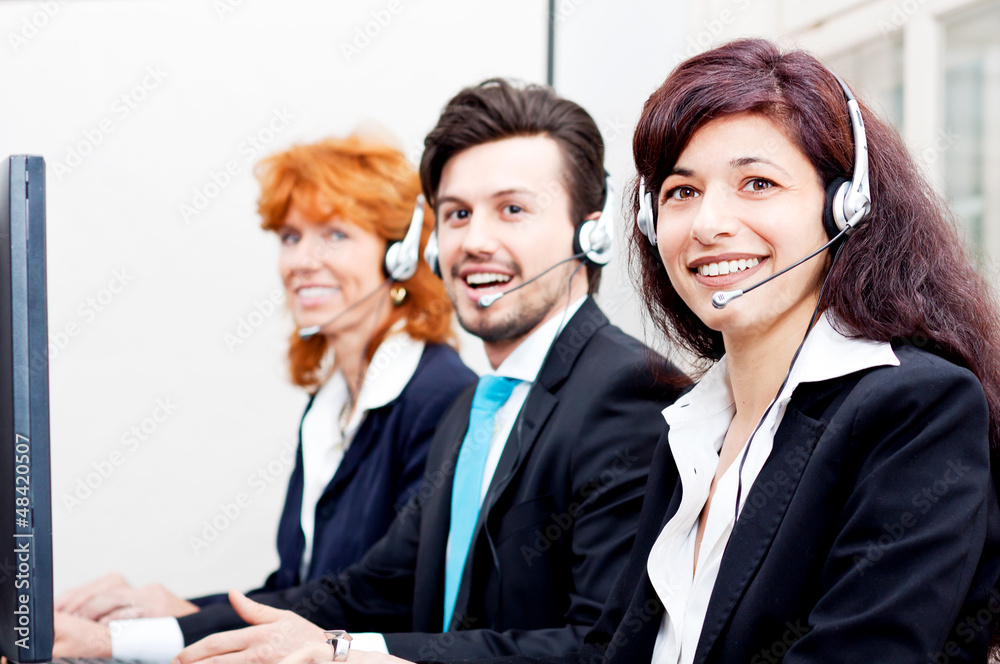 Callcenter Mitarbeiter mit Kopfhörern am Computer freundlich Callcenter Mitarbeiter mit Kopfhörern am Computer freundlich
