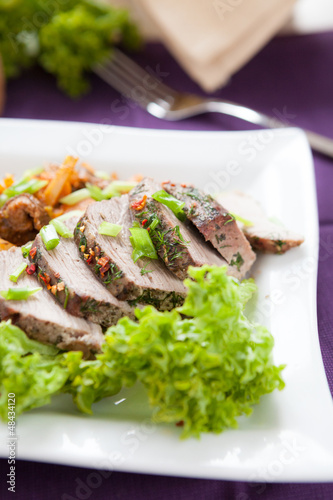 baked meat with lettuce on a square plate