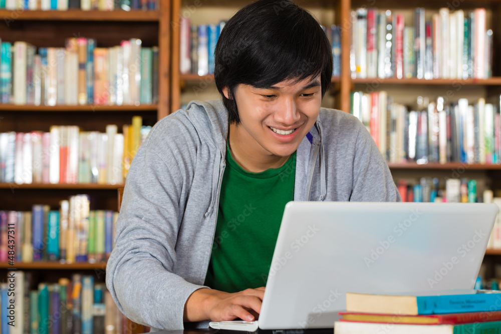 Asian man in library with laptop Asian man in library with laptop