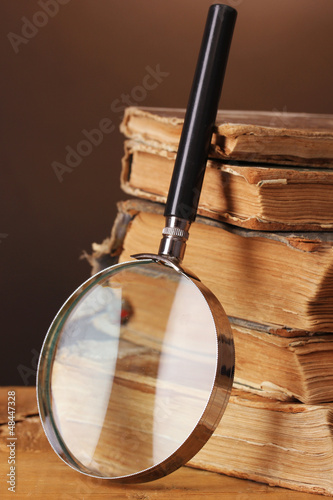 Magnifying glass and books on brown background