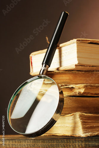 Magnifying glass and books on table