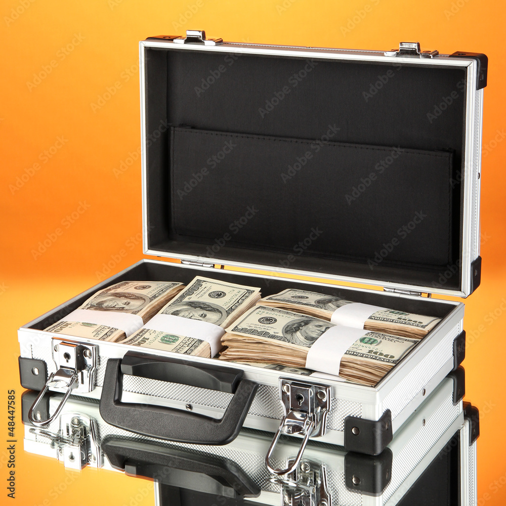 Suitcase with 100 dollar bills on orange background Suitcase with 100 dollar bills on orange background