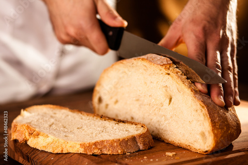 Baker Slicing Bran Bread on a Cutting Board