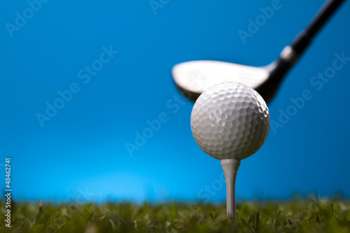 Golf ball on green grass over a blue background 