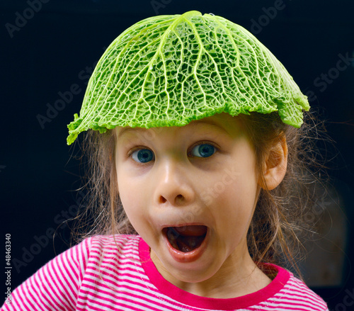 little girl with leaf of savoy cabbage instead of a hat