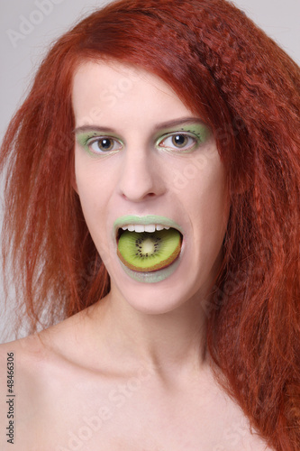 girl with kiwi slice on her mouth