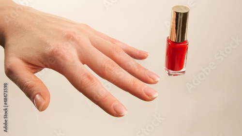Weibliche Hand mit rotem Nagellackfläschchen photo