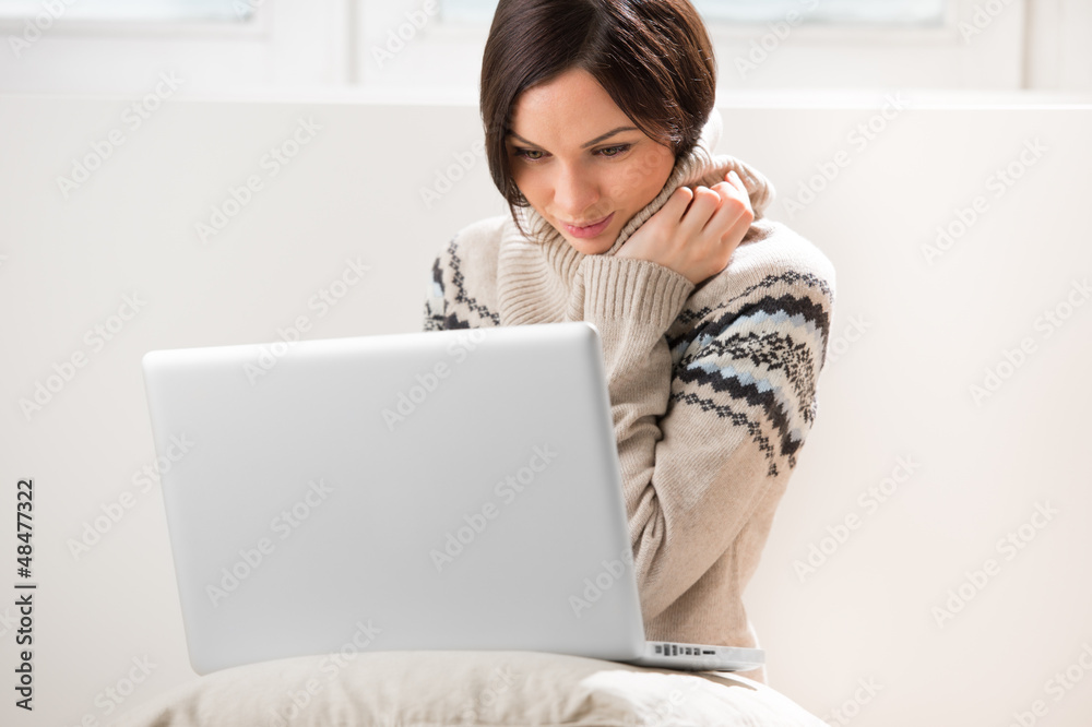 A young woman sitting on the floor in front of her laptop, looki A young woman sitting on the floor in front of her laptop, looki