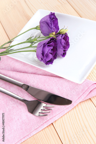 Fototapeta Naklejka Na Ścianę i Meble -  Tableware with flower on bright napkin close-up