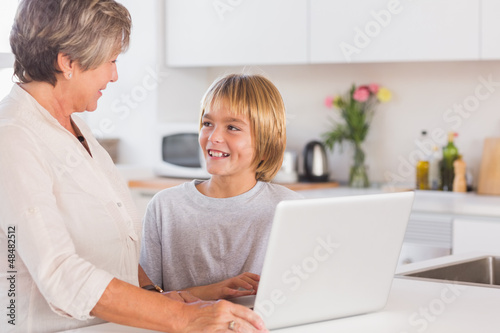 Granny and grandson using laptop and smiling