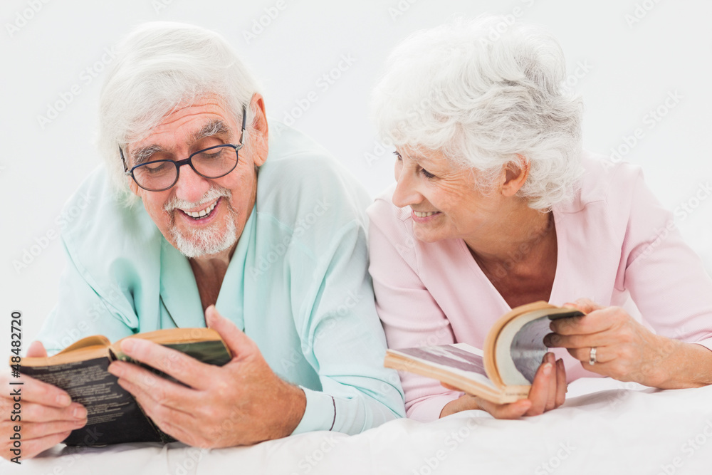 Happy husband and wife reading in bed Happy husband and wife reading in bed