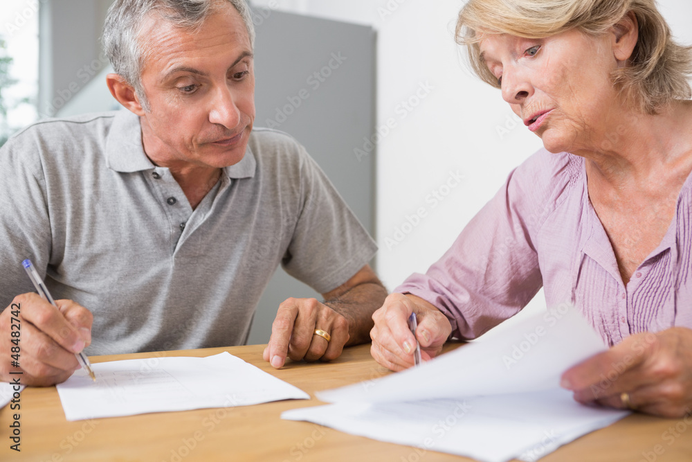 Mature couple discussing with documents Mature couple discussing with documents