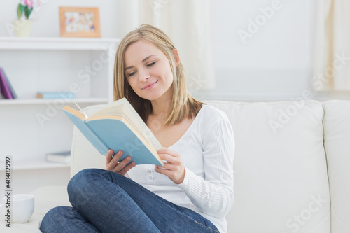 Happy woman reading storybook at home
