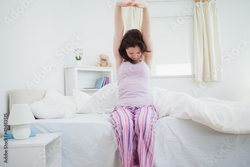Sleepy young woman stretching her arms up
