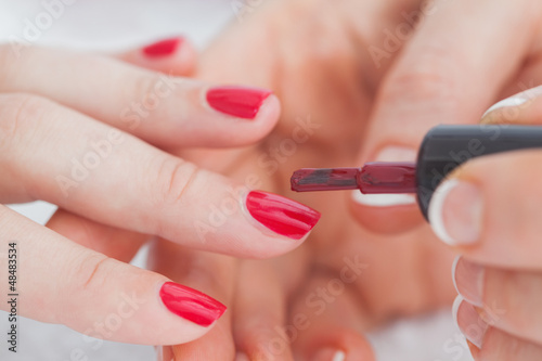 Details shot of hands applying red nail varnish to nails Fototapet