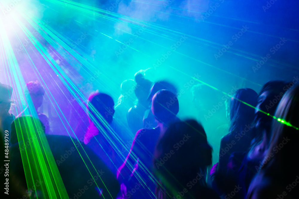 Party people dancing under laser light.