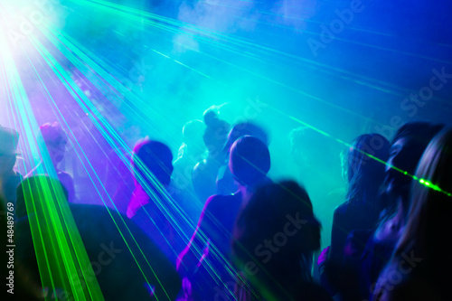 Party people dancing under laser light.
