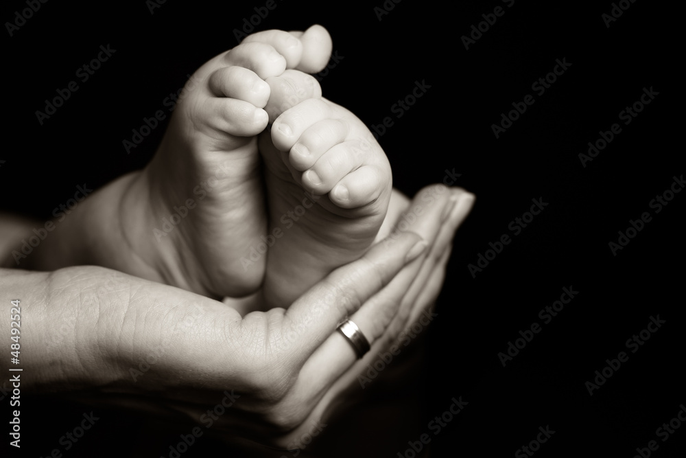 Mother gently holding her baby foot Mother gently holding her baby foot