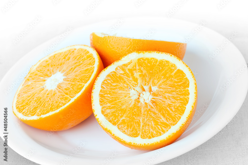 Fototapeta premium Sliced fresh orange fruit on a white plate