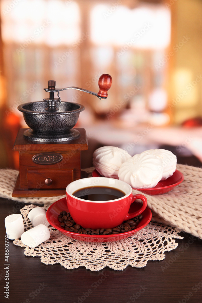 cup of coffee with scarf and coffee mill on table in room