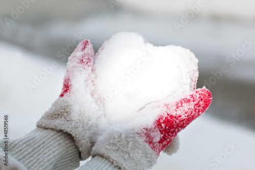 Hands hold snow like a heart