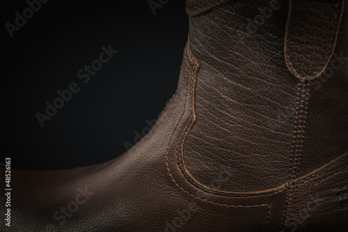 Extreme close-up of a brown leather cowboy boot on black