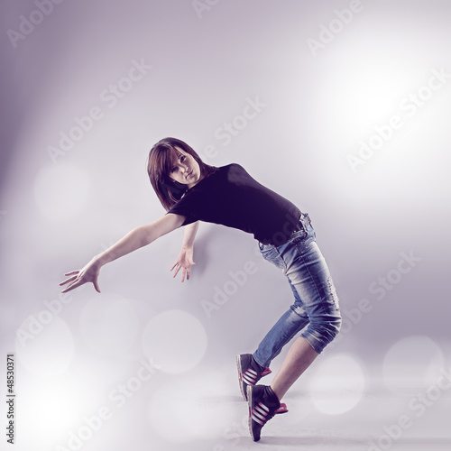 Teenage girl dancing hip-hop leaning on back in studio
