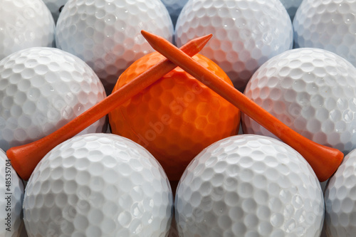 An closeup of a regular a orange golf tees on a golf balls