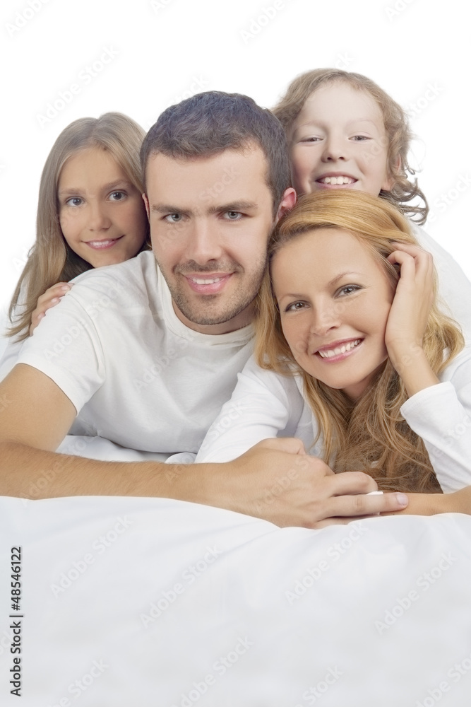 family smiling while laying on bed covered with white linen