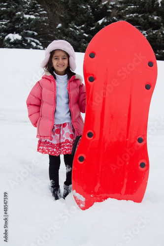 East Indian girl toboganning in the snow photo