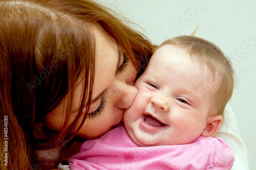 Mother kissing baby, kid laughing.