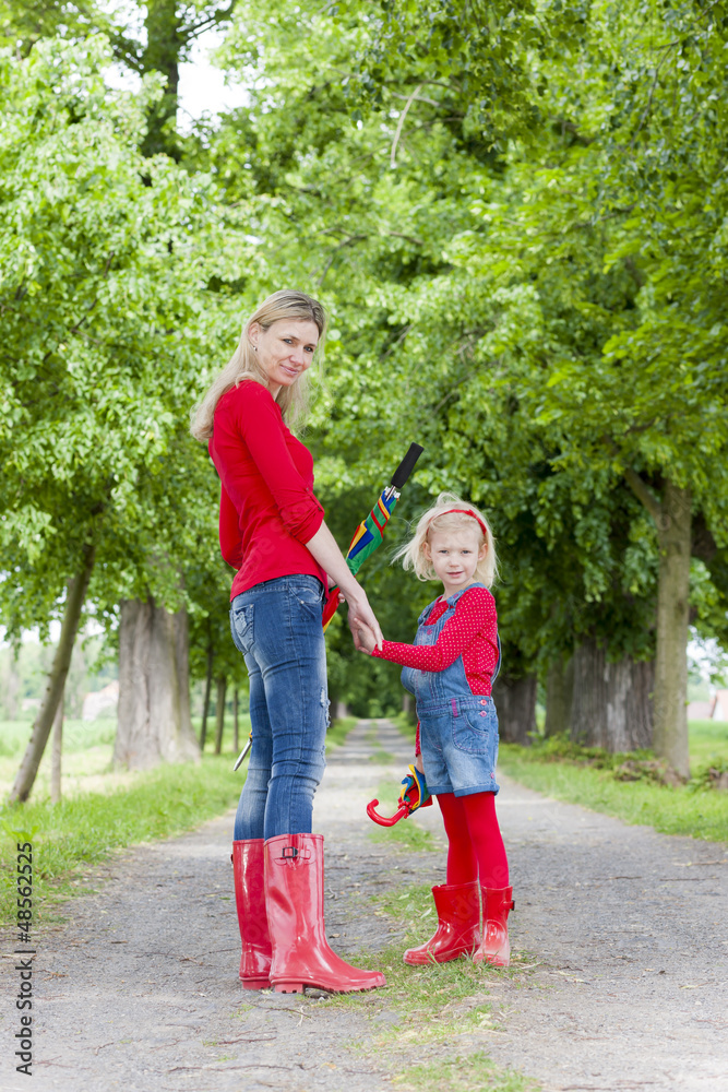 Fototapeta premium mother and her daughter with umbrellas in spring alley