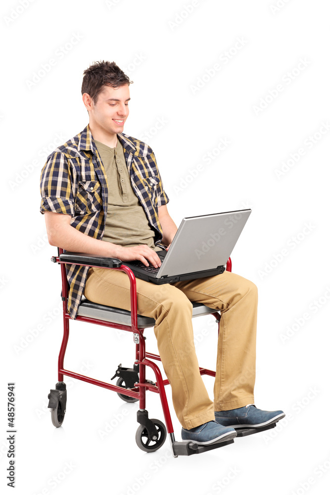 Young disabled man in a wheelchair working on a laptop