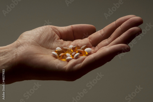 Closeup of hand holding vitamin E and vitamin D capsules